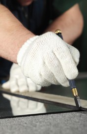 The worker, cutting a mirror,focus on a hand with tool
